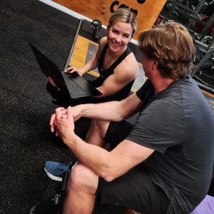 Catalyst 24/7 Fitness personal trainer holding laptop with gym member