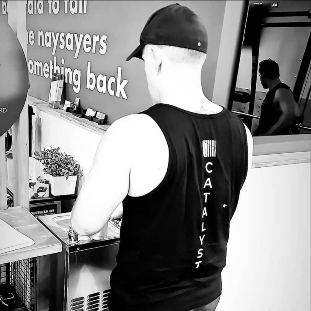 Man wearing Catalyst 24/7 Fitness singlet standing at the bubbler